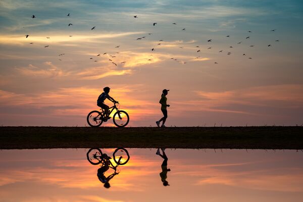 un cycliste et un jogger en ombres chinoises sur un coucher de soleil