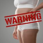une femme tient ses poignées d'amour sur cette photo un warning en rouge